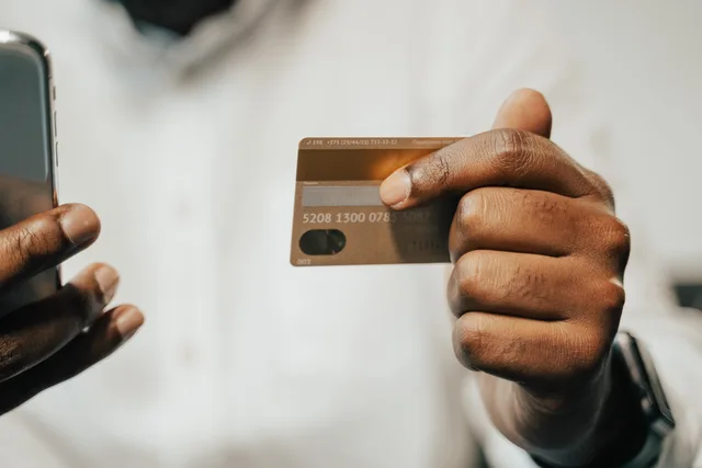Person using a smartphone and credit card for online shopping or payment. Betalingsmetoder danske kunder forventer i en webshop