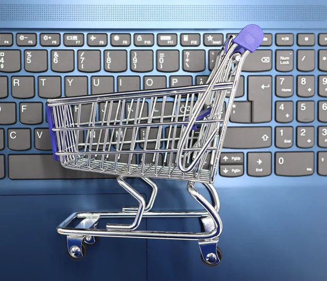 A miniature shopping cart placed on a laptop keyboard symbolizing online shopping and e-commerce. Hvilke krav stiller e-handelsloven til en webshop?